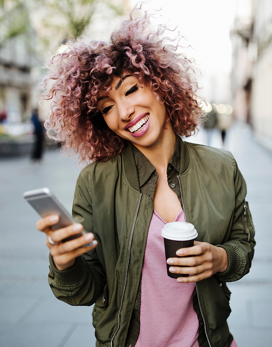 smiling girl holding a cup of coffee and a cellular phone